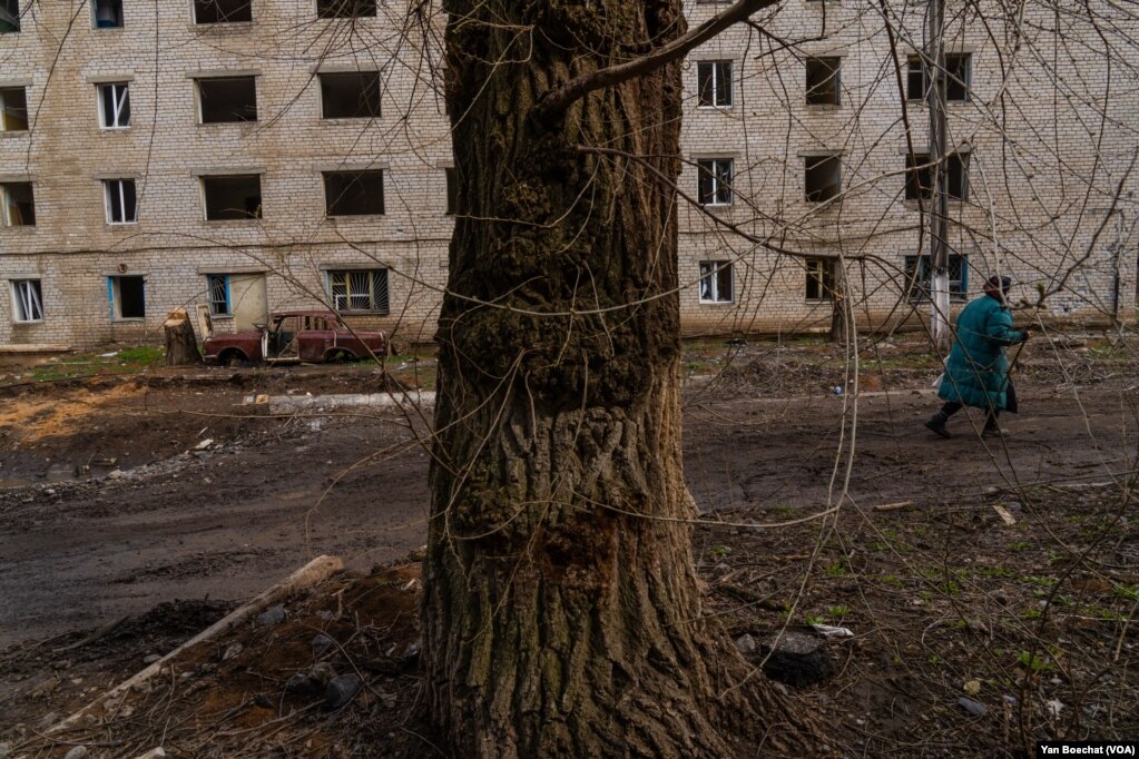 Жінка проходить повз зруйновану автівку на одній із численних вулиць, які постраждали від російської артилерії у Сіверську, 4 квітня 2023 року